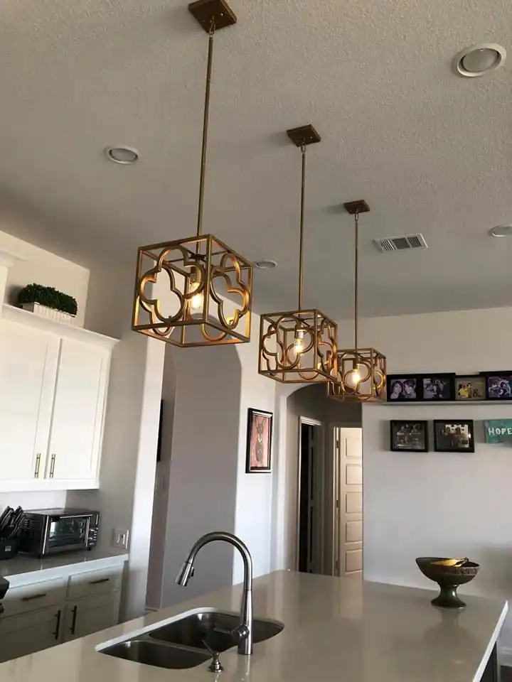 Three brass pendant lights installed over a kitchen island in a Hutto home
