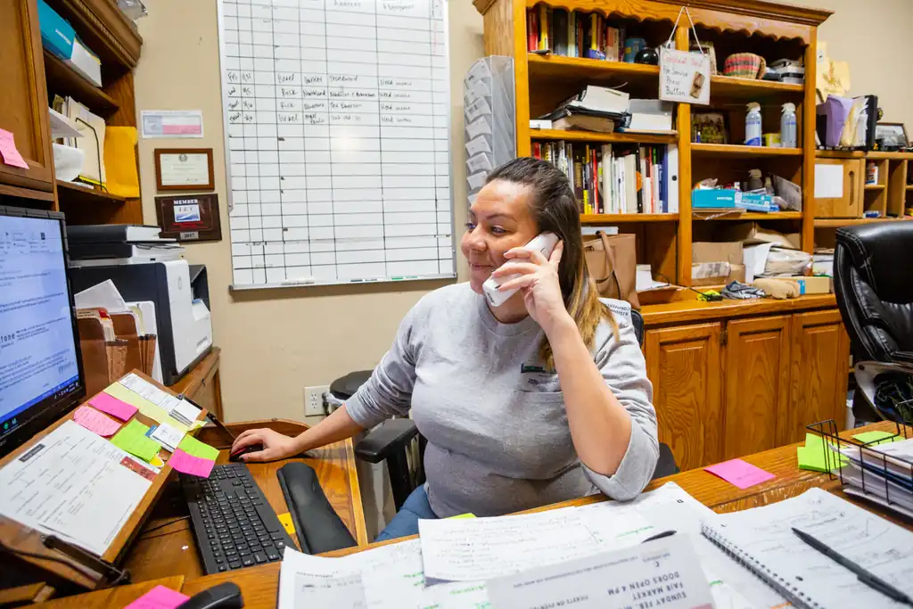 Office interior with a staff member on the phone and the IEC member plaque on the shelf behind her