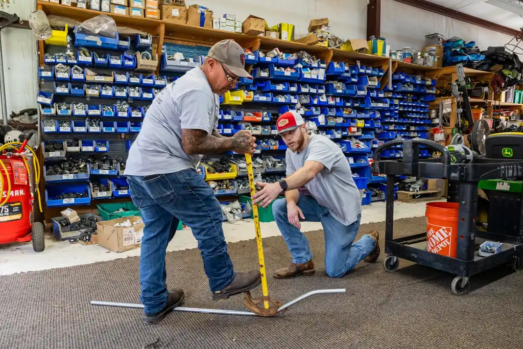 Two Lightning Electrical staff bending conduit with a hand bender in the stocked parts shop